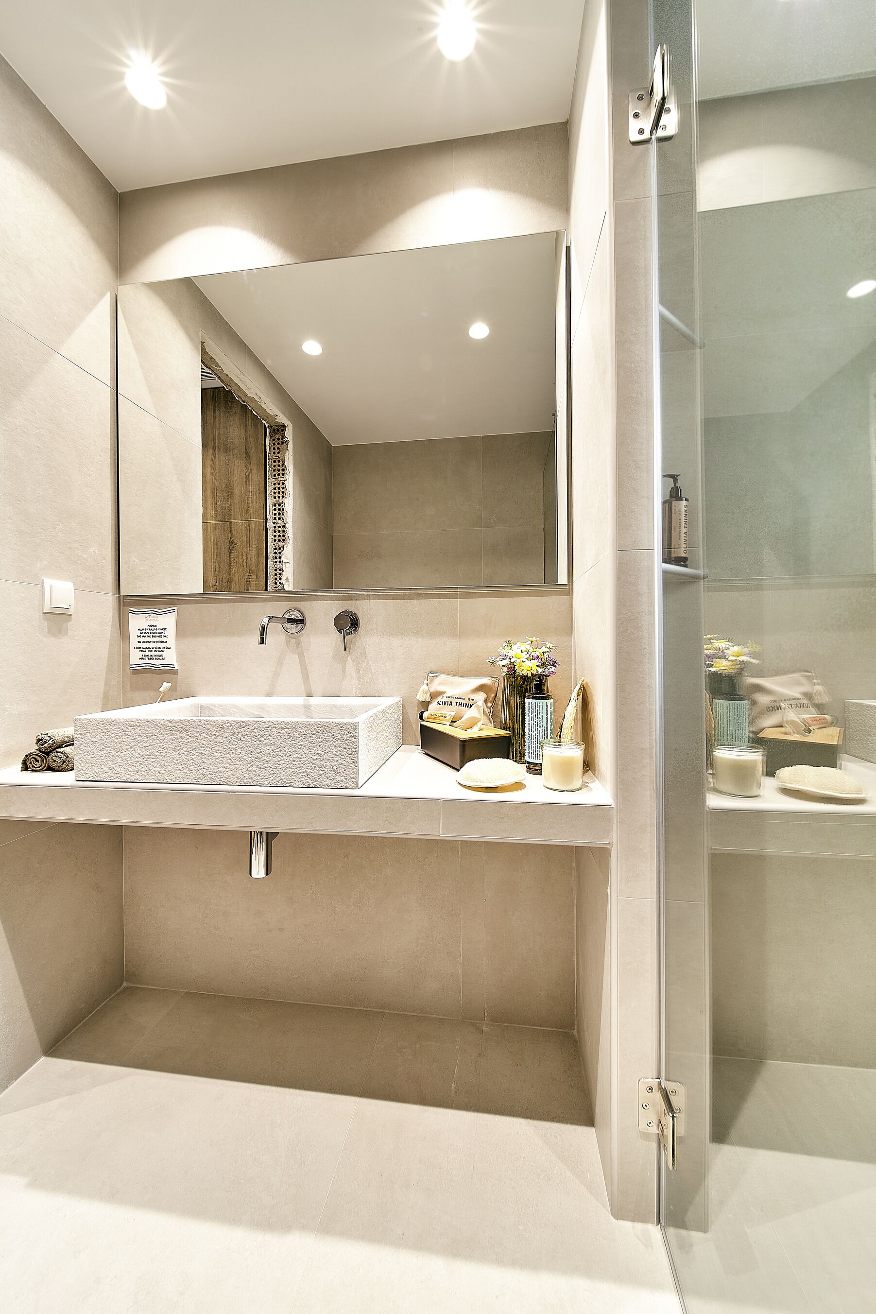 A modern bathroom with a large mirror, a rectangular sink, and a glass shower enclosure.