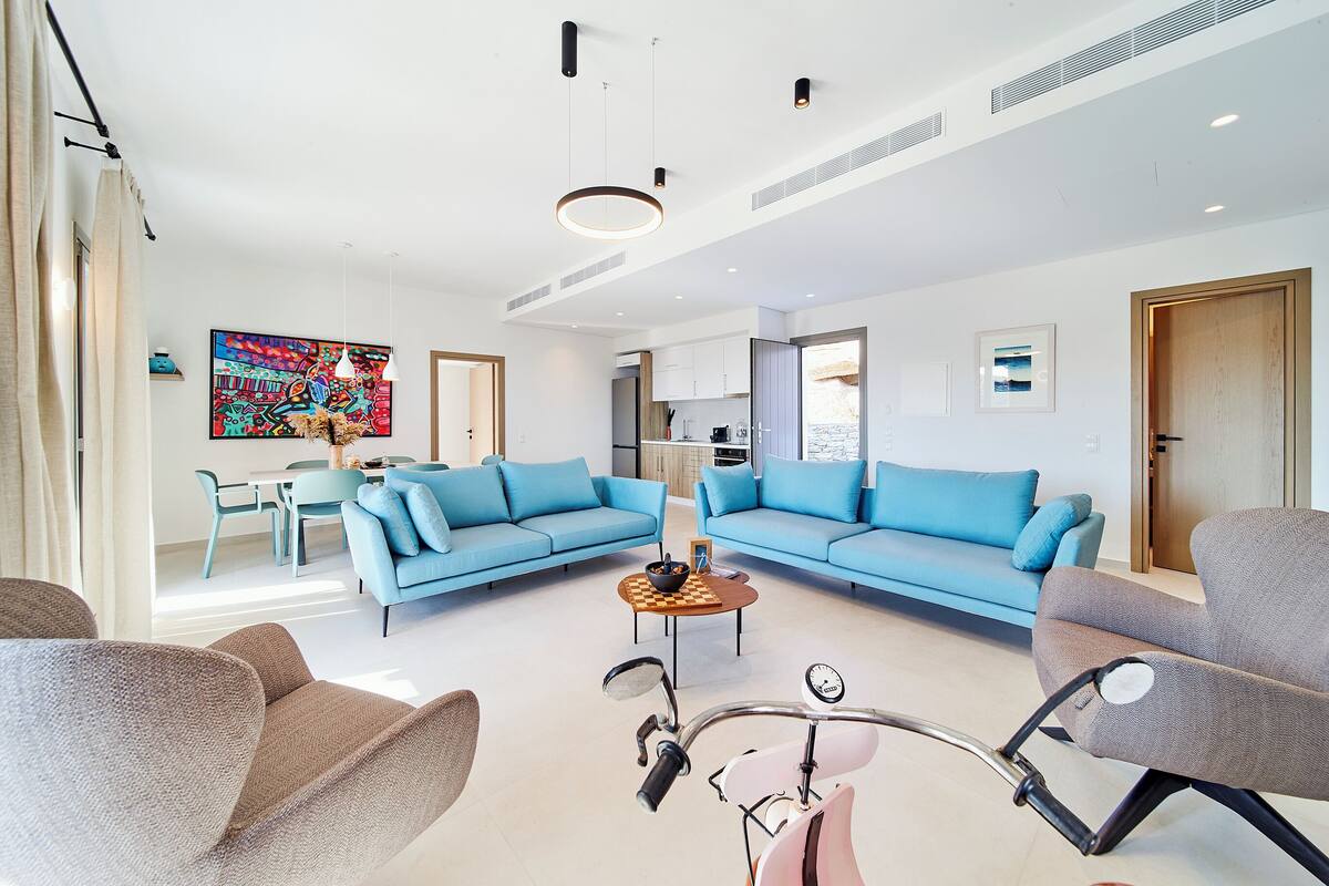 A modern living room with two blue sofas, a coffee table, and a bicycle.