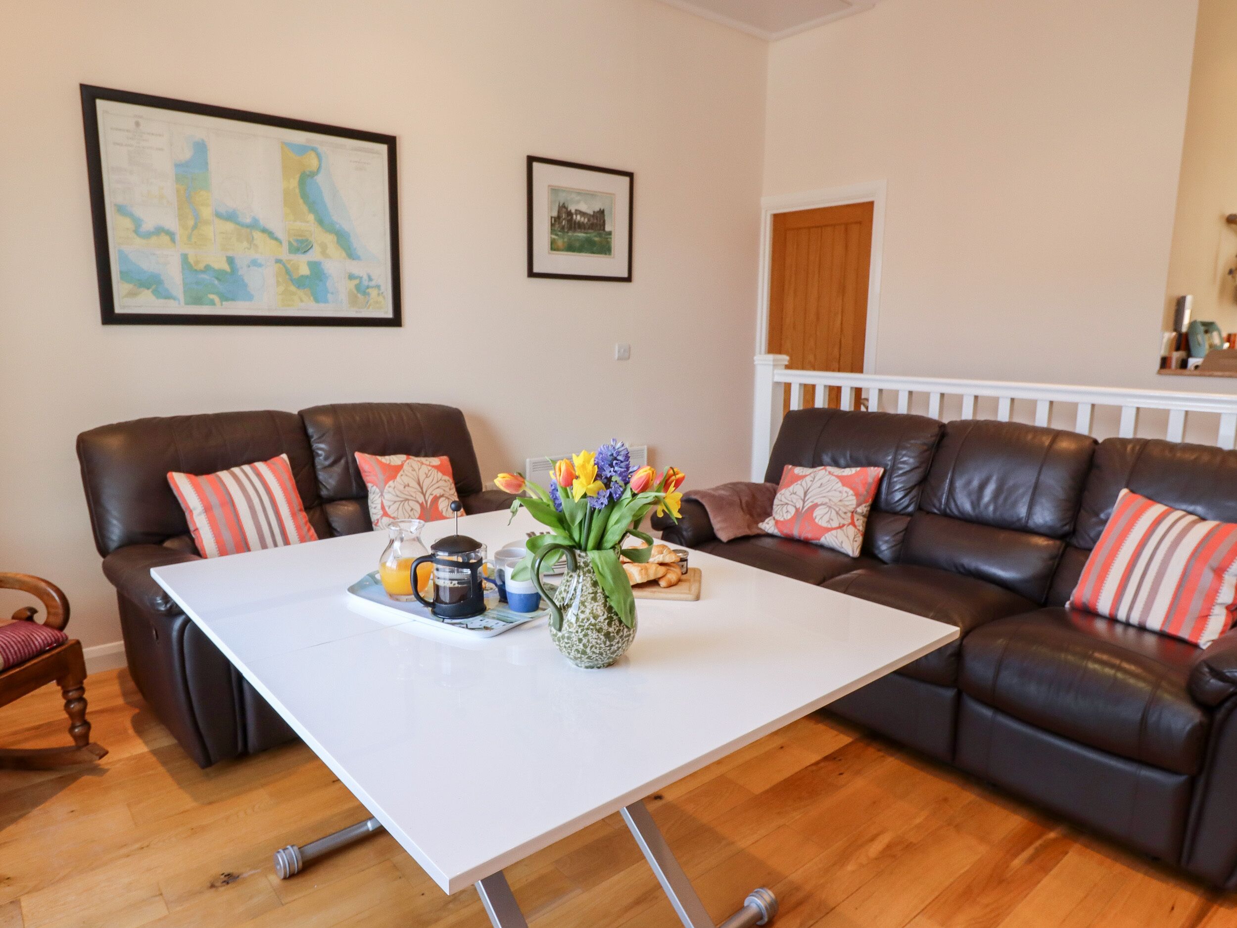 A living room with two dark brown leather sofas, a white coffee table, and a framed map on the wall.