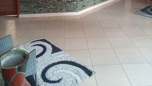 A reception area with a stone counter, tiled floor, and a clock on the wall. - samanene hotels limited (Mwanza)