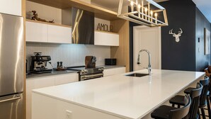 Une cuisine moderne dotée d’un îlot central, d’appareils électroménagers en acier inoxydable et d’une palette de couleurs en noir et blanc.