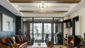 Un salon moderne avec un canapé en cuir, des chaises en bois, une table basse et une cheminée.