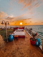 Terraza con tumbonas y vista al atardecer sobre el mar.