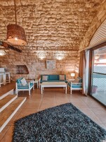 Una habitación acogedora con pared de piedra, un conjunto de sofás, una mesita de centro y un tapete grande.