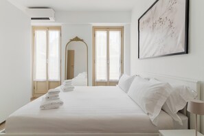 Une chambre d’hôtel avec un lit soigneusement fait, un grand miroir et une œuvre d’art encadrée accrochée au mur.