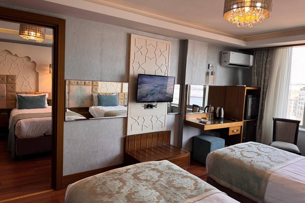 Habitación de hotel con dos camas, televisión, escritorio y minibar.