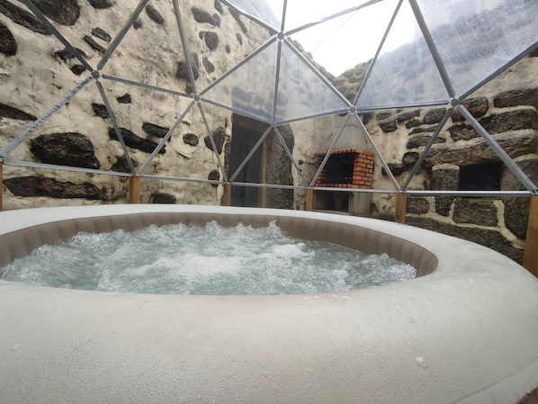 A hot tub in a stone-walled room with a geometric glass ceiling.