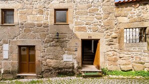 Un edificio de piedra con suelo adoquinado, una puerta de madera y una escalera que conduce a un nivel superior.