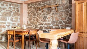 Un comedor rústico con pared de piedra, mesa y sillas de madera.