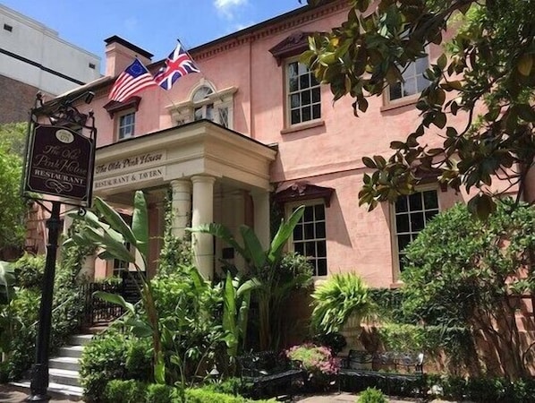 Um edifício rosa com uma placa que diz "The Old Pink House Restaurant" e bandeiras.