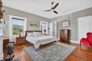 A bedroom with a bed, dresser, red chair, and a ceiling fan. - York Street Living! Off-Street Parking, Dog Friendly! (Savannah)