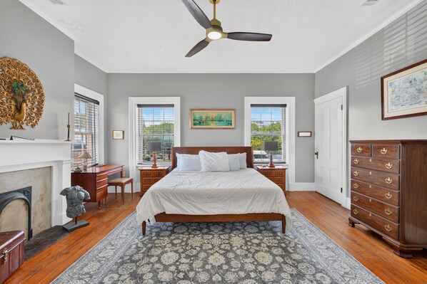 A bedroom with a bed, a ceiling fan, a fireplace, a desk, and a dresser. - York Street Living! Off-Street Parking, Dog Friendly! (Savannah)