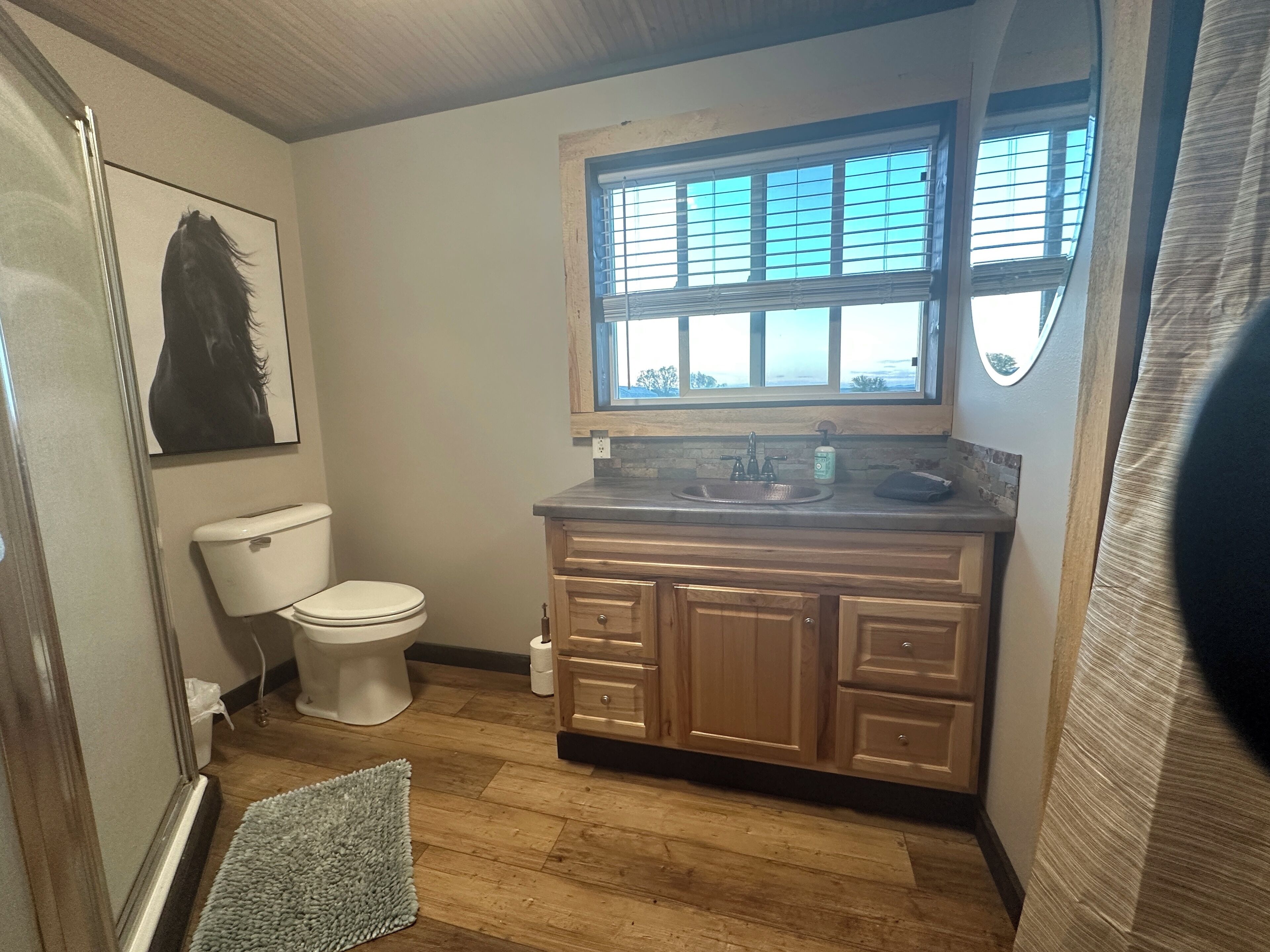 A bathroom with a toilet, sink, and window.