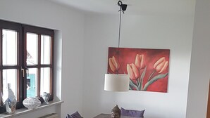 Un coin repas avec une table en bois, des chaises en osier et un tableau représentant des tulipes rouges.