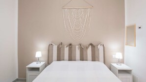 Ein Schlafzimmer mit einem großen Bett, zwei Nachttischen mit Lampen und einer Wanddekoration aus Makramee darüber.