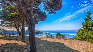 A beach with a view of the ocean, trees, and a few chairs and a bench. - Buckhorn Cove Ocean Front with Private Peninsula (Little River)