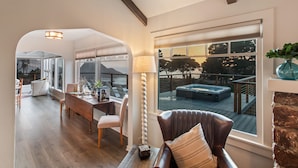 A spacious living area with a view of a hot tub and deck, a dining area with a table and chairs, and a cozy seating area with a lamp and fireplace. - Buckhorn Cove Ocean Front with Private Peninsula (Little River)