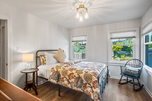 Une chambre à coucher avec un lit, une chaise, une lampe et des fenêtres équipées de stores.