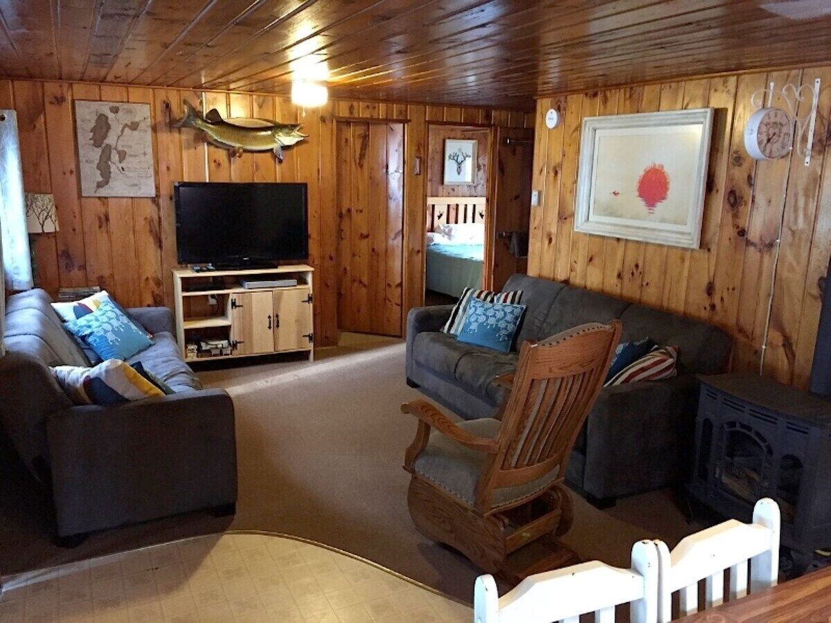 Een gezellig chaletinterieur met houten inrichting, een televisie, een open haard en een comfortabele zithoek.