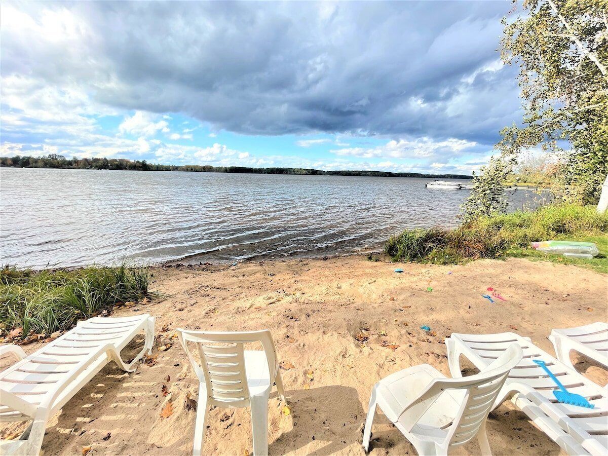A beach with white plastic chairs and a sandy shore.