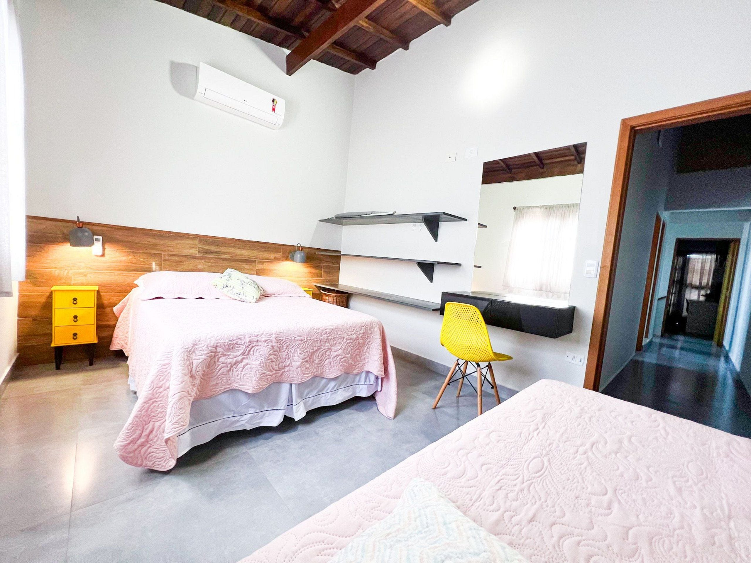 A bedroom with a bed, a nightstand, a chair, a desk, and a mirror.