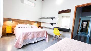 A bedroom with a bed, a nightstand, a chair, a desk, and a mirror.