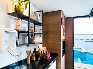 A modern kitchen with a coffee machine, wooden utensils, and a view of a swimming pool.