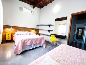 Un dormitorio con cama, mesita de noche, silla, escritorio y espejo.