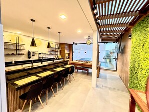 A modern kitchen with a pool table, bar area, and a green wall.