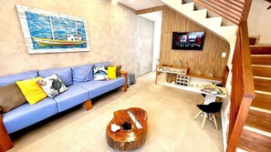 Una sala de estar moderna con un sofá azul, una mesa de centro de madera y un televisor montado en una pared de madera.