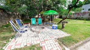 Un patio con mobiliario exterior, una chimenea y un parasol verde.