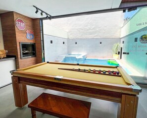 Una mesa de billar con vistas a un jacuzzi y una piscina exterior.