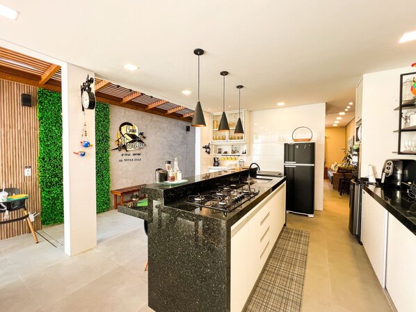 A modern kitchen with a central island, black appliances, and pendant lighting.