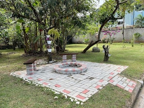 A garden with a fire pit, benches, and a brick pathway.