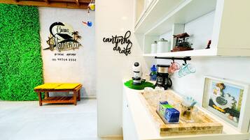 A modern kitchen with a green wall, a wooden bench, and a coffee station.