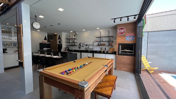 A pool table with balls, a kitchen area, and a 'STOP Route 66' sign. - Casas Marimar Ilheus (Caraguatatuba)