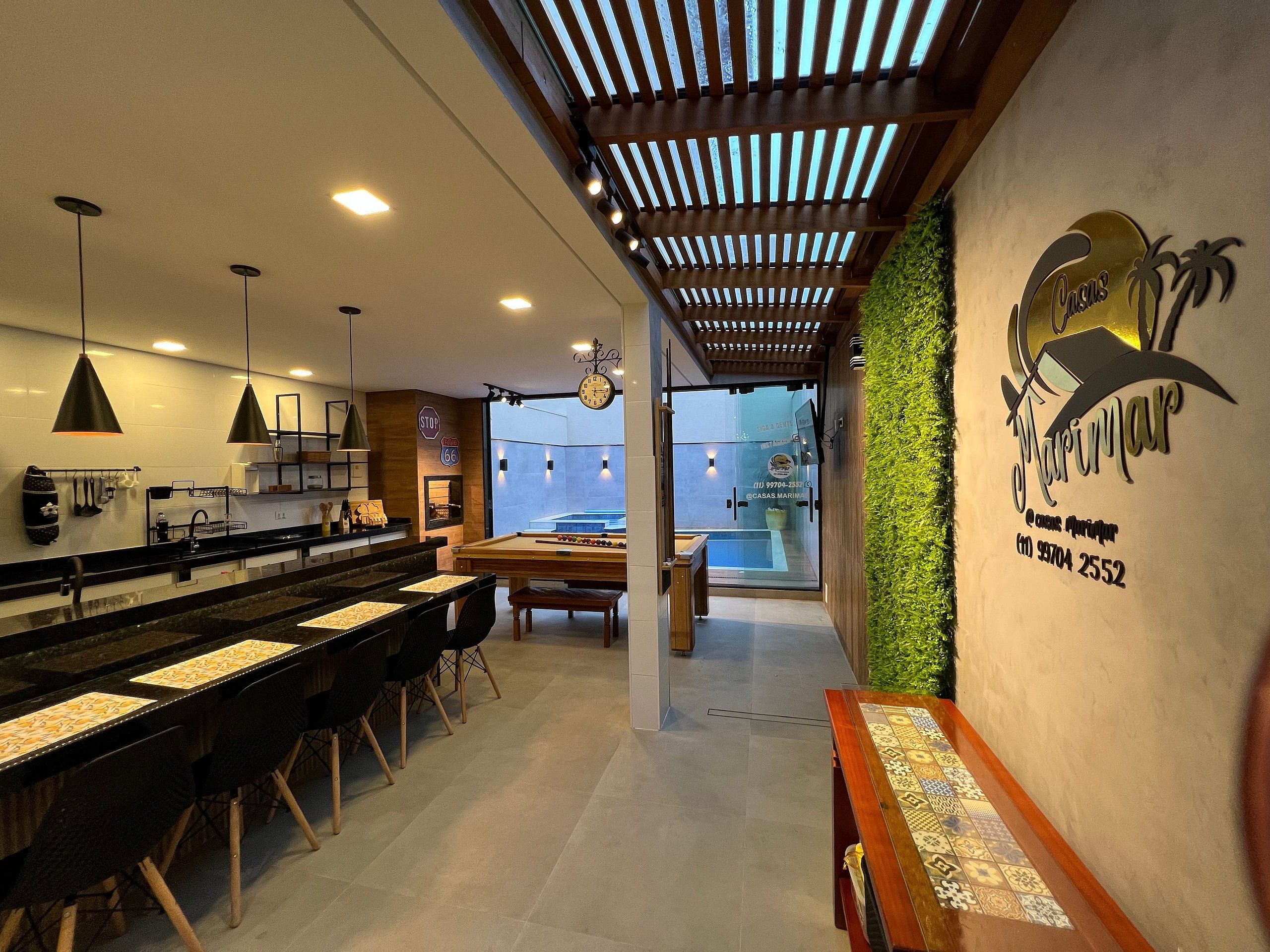 Un área de bar moderna con mesa de billar, taburetes y piscina.