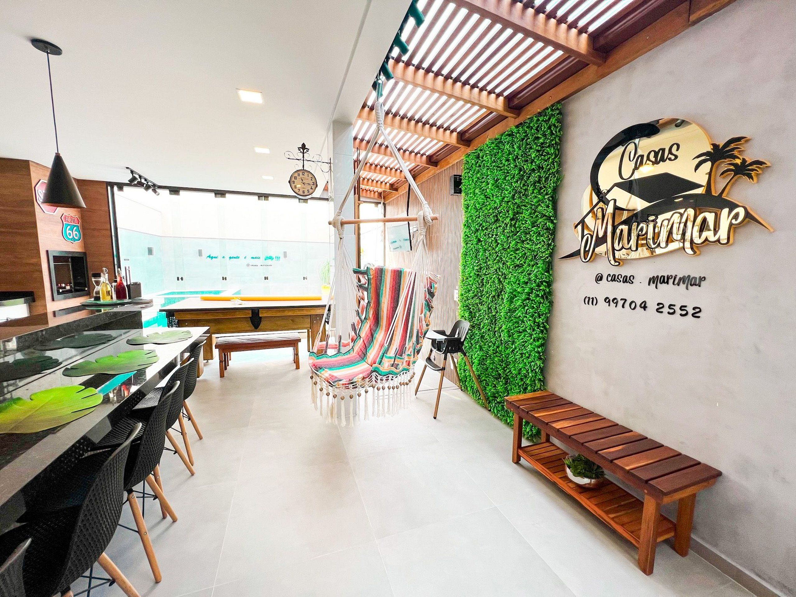 A modern interior with a bar area, a green wall with a logo, and a wooden bench.