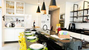 Une cuisine moderne avec des meubles blancs, un plan de travail noir et des chaises jaunes.