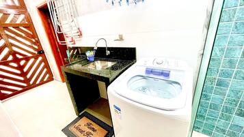Une petite salle de bain comprenant un lavabo, un lave-linge et un espace douche.