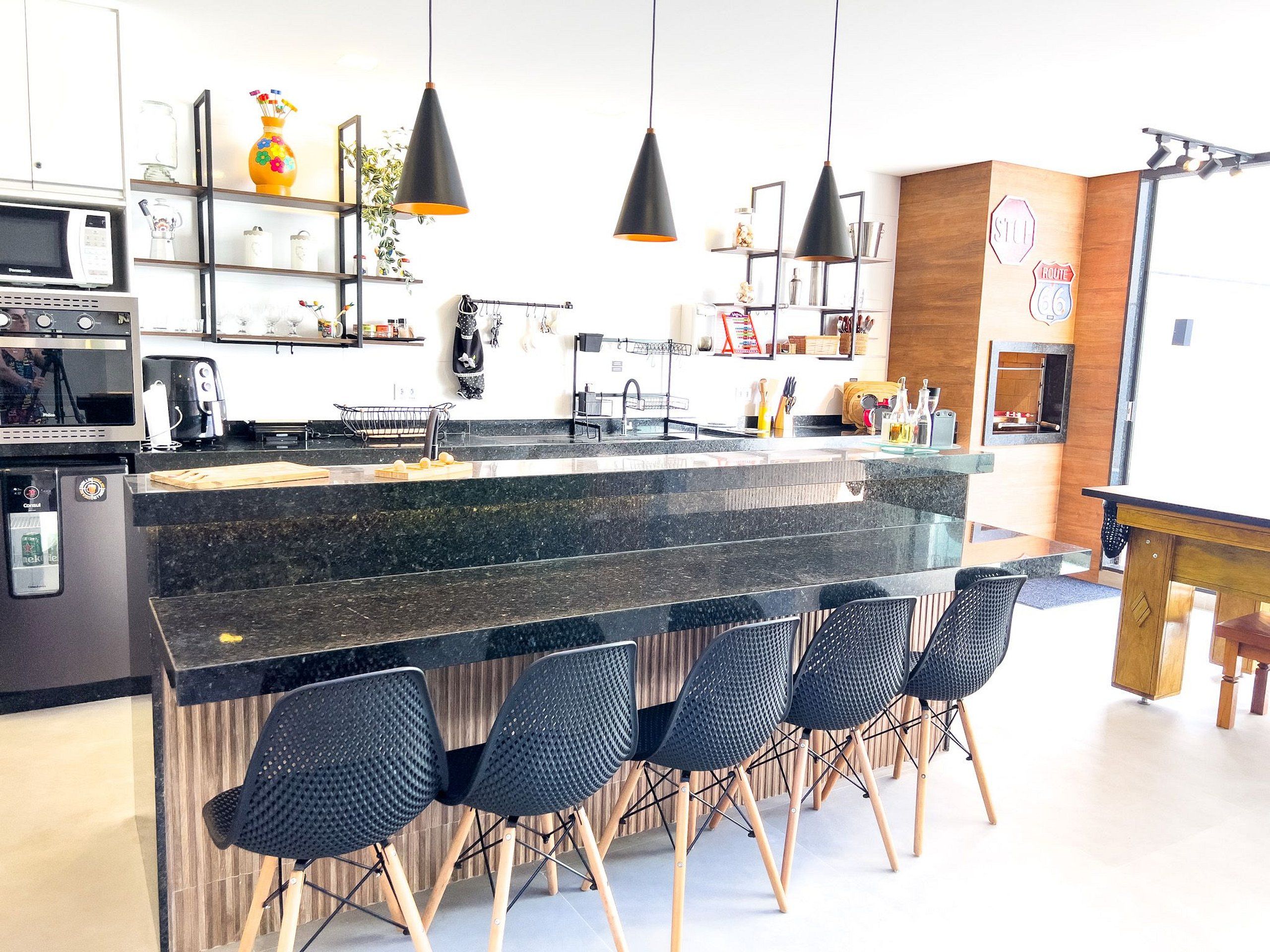 Una cocina moderna con una isla central, taburetes de bar, iluminación colgante y un cartel de la Ruta 66.