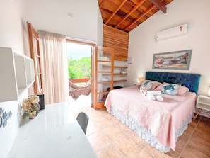 Een slaapkamer met een bed, een stoel, een tafel, een plank en een raam.