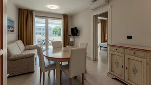 Une chambre d’hôtel comprenant un coin repas, un canapé, une télévision et donnant sur l’extérieur.