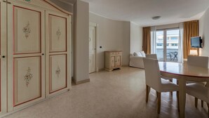A hotel room with a dining area, a small cabinet, and a television mounted on the wall. - Apt24 - Relais du Lac 216 (Desenzano del Garda)