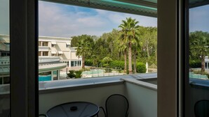 A balcony with a pool view, a round table, and a chair. - Apt24 - Relais du Lac 216 (Desenzano del Garda)