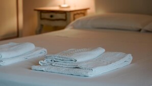 A neatly made bed with folded white towels and a bedside table with a lamp. - Apt24 - Relais du Lac 216 (Desenzano del Garda)