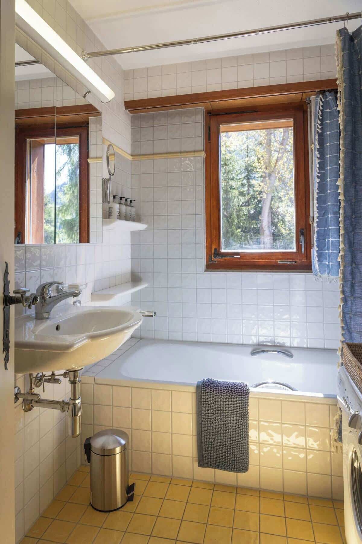 Une salle de bain avec deux lavabos, une baignoire, une fenêtre et un porte-serviettes.