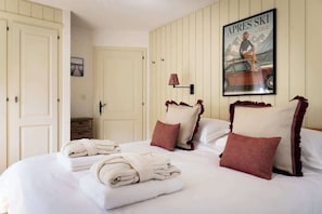 A hotel room with a bed, pillows, a poster, and a lamp. - 3BR Central: Pool, Sauna, Gym & Views (Verbier)