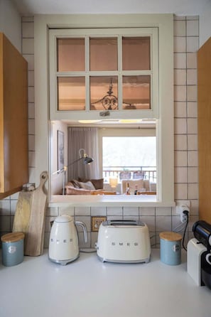 Une cuisine avec une fenêtre, un grille-pain, une bouilloire et une lampe.