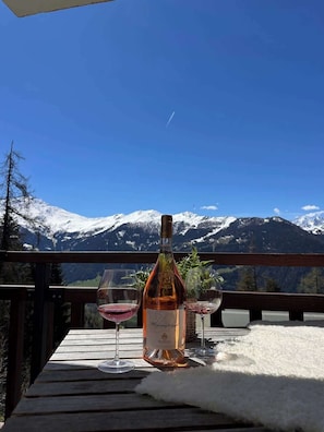 Une table avec une bouteille de vin et deux verres, le tout placé devant un paysage de montagne.